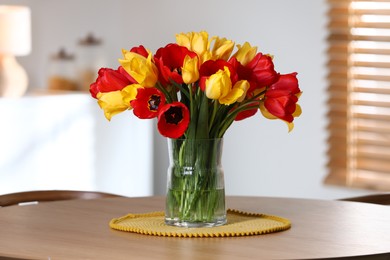 Photo of Beautiful tulips in vase on wooden table indoors