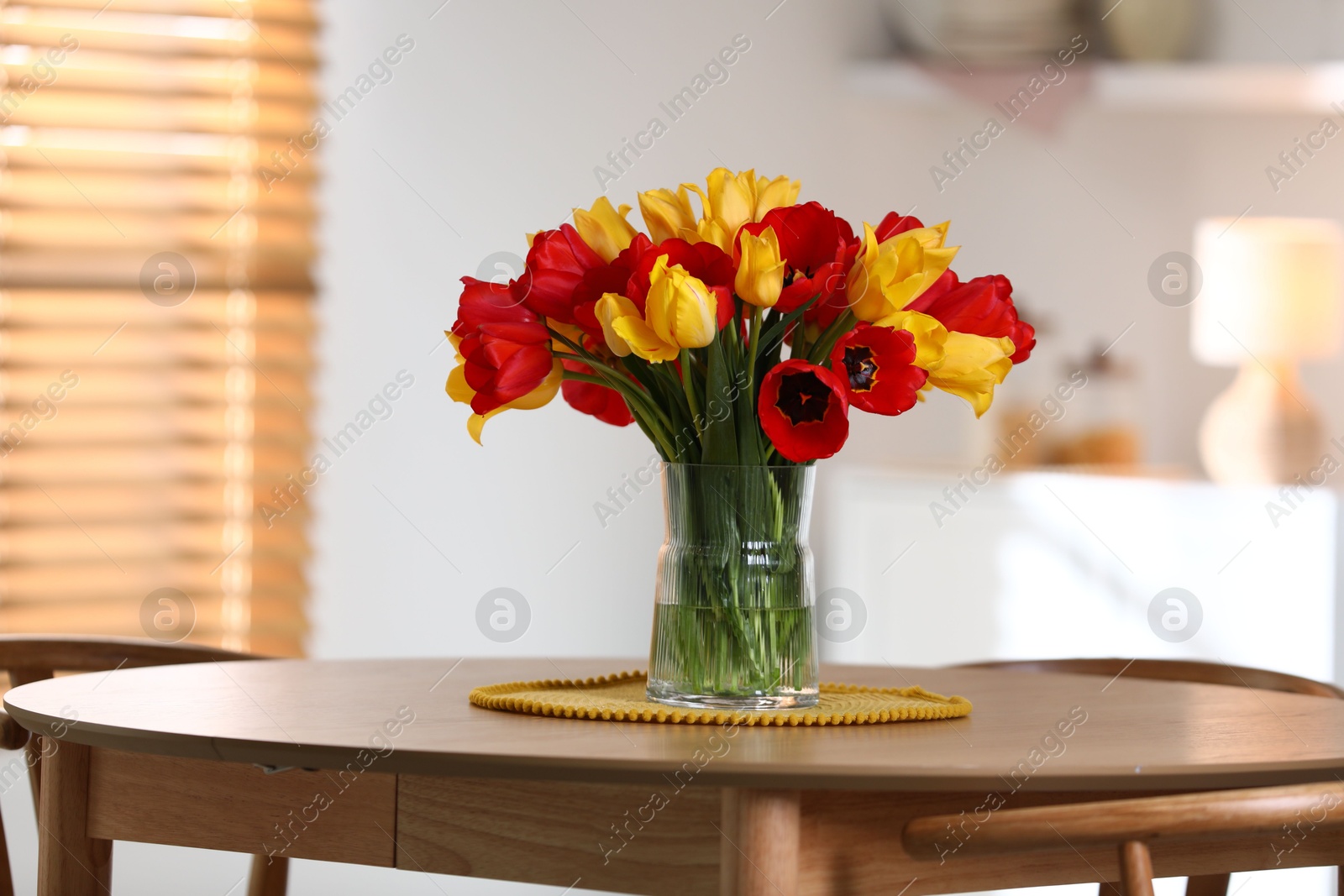 Photo of Beautiful tulips in vase on wooden table indoors