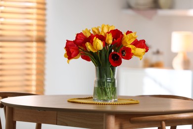 Photo of Beautiful tulips in vase on wooden table indoors