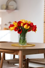 Photo of Beautiful tulips in vase on wooden table indoors