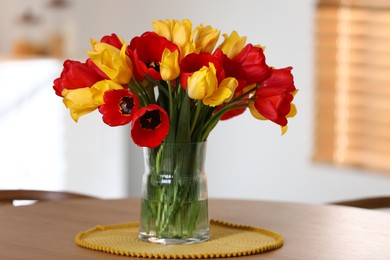 Photo of Beautiful tulips in vase on wooden table indoors
