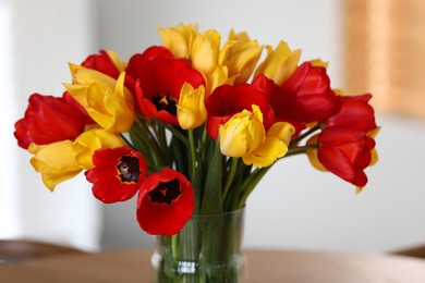 Photo of Beautiful tulips in vase on wooden table indoors, closeup