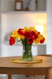 Photo of Beautiful tulips in vase on wooden table indoors