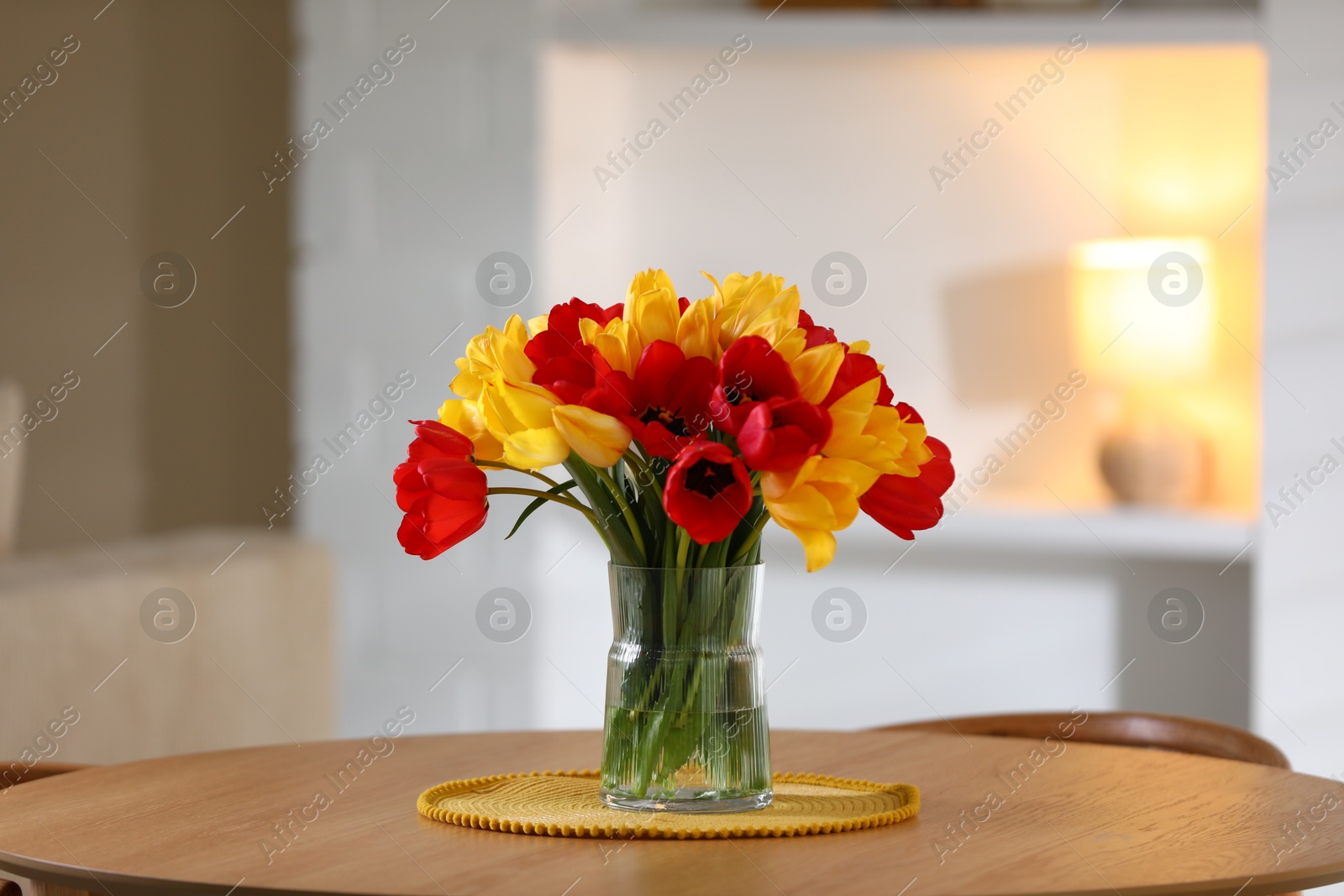 Photo of Beautiful tulips in vase on wooden table indoors