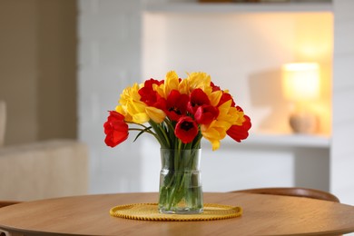 Photo of Beautiful tulips in vase on wooden table indoors