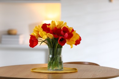 Photo of Beautiful tulips in vase on wooden table indoors