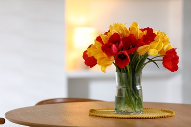 Photo of Beautiful tulips in vase on wooden table indoors. Space for text