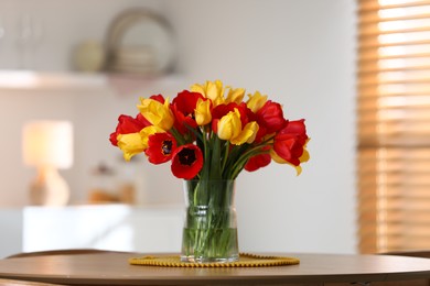 Photo of Beautiful tulips in vase on wooden table indoors