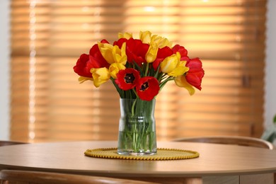 Photo of Beautiful tulips in vase on wooden table indoors