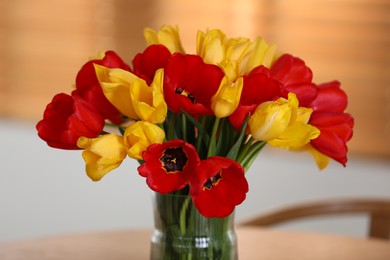 Photo of Beautiful tulips in vase on wooden table indoors, closeup