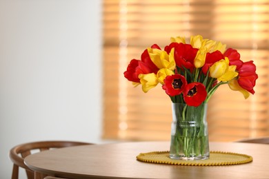 Photo of Beautiful tulips in vase on wooden table indoors. Space for text