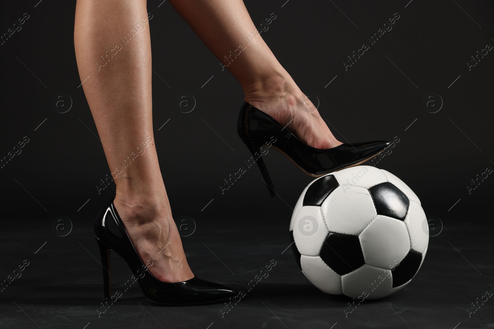 Woman in high heeled shoes with soccer ball on dark background, closeup Photo of Woman in high heeled shoes with soccer ball on dark background, closeup