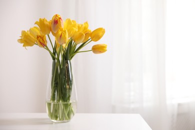 Photo of Bouquet of beautiful tulips on table near white wall. Space for text