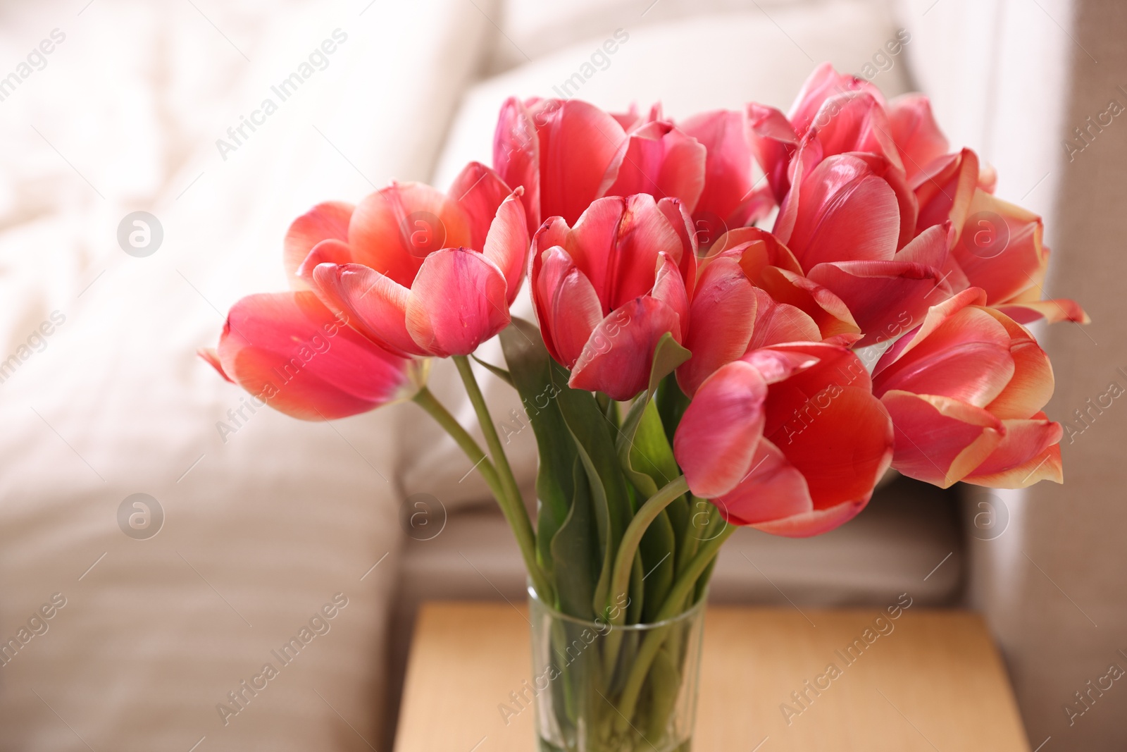 Photo of Bouquet of beautiful tulips on side table in bedroom, closeup