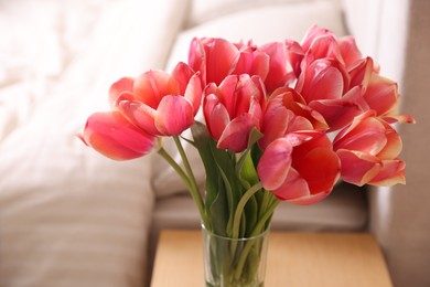 Photo of Bouquet of beautiful tulips on side table in bedroom, closeup