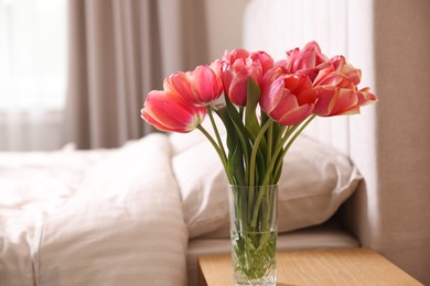 Photo of Bouquet of beautiful tulips on side table in bedroom