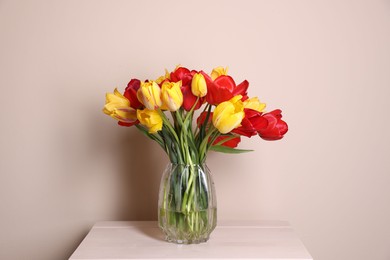 Photo of Bouquet of beautiful tulips on table against beige background