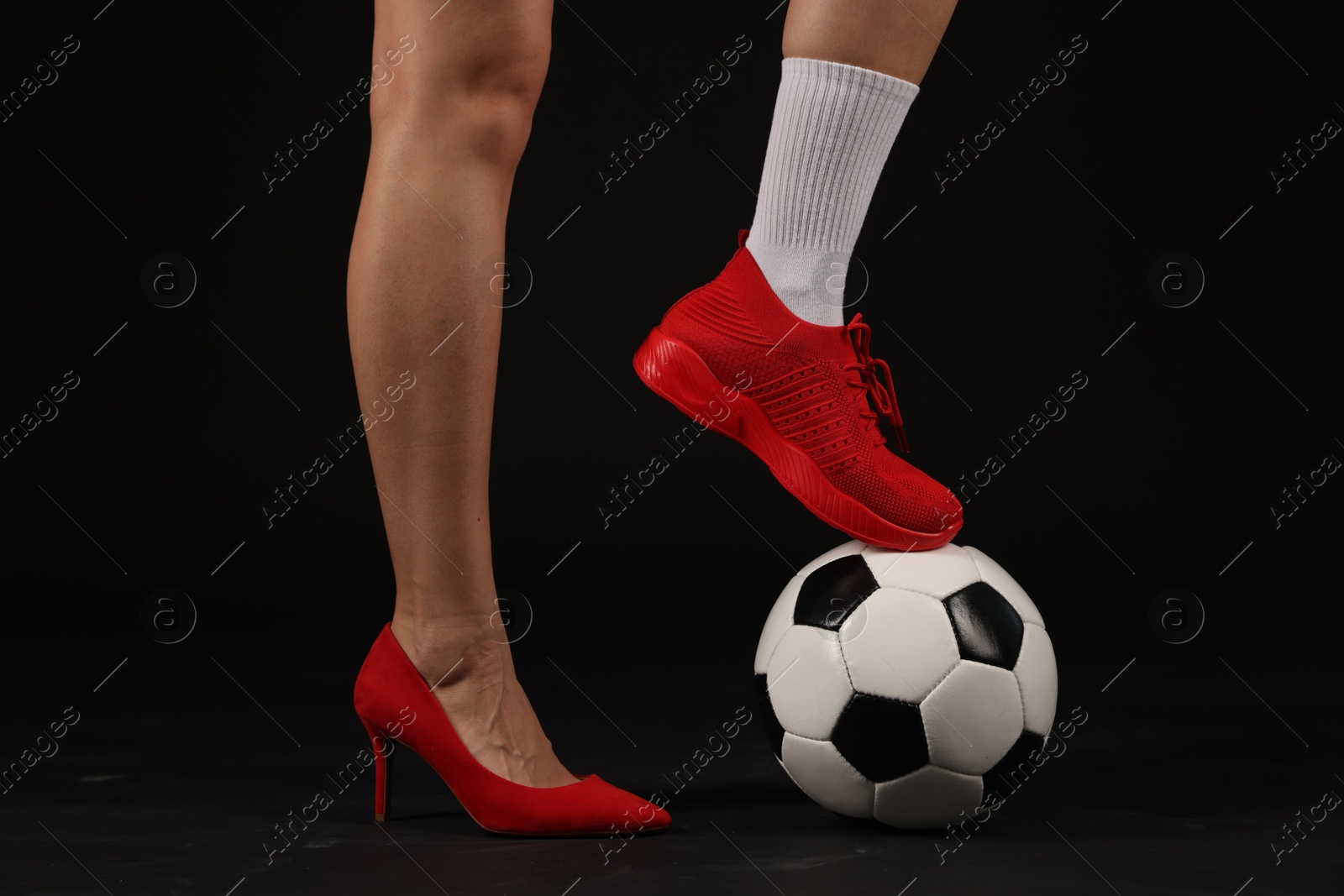 Woman in high heeled shoe and sneaker with soccer ball on dark background, closeup Photo of Woman in high heeled shoe and sneaker with soccer ball on dark background, closeup