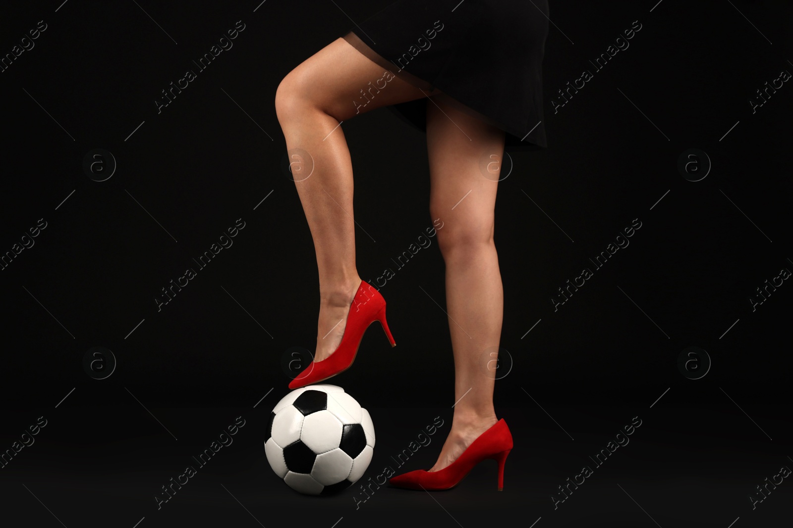 Woman in high heeled shoes with soccer ball on dark background, closeup Photo of Woman in high heeled shoes with soccer ball on dark background, closeup