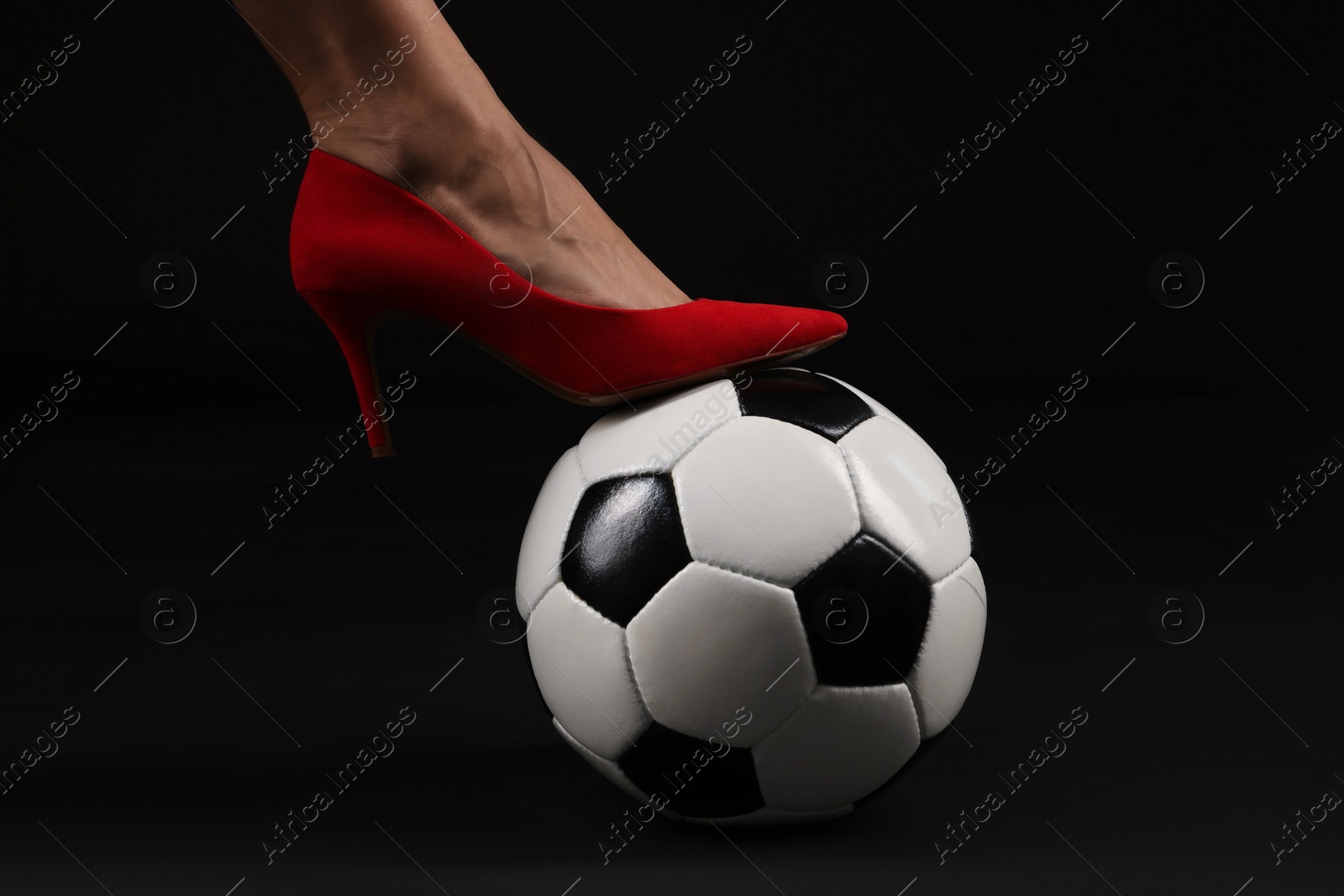 Woman in high heeled shoe with soccer ball on dark background, closeup Photo of Woman in high heeled shoe with soccer ball on dark background, closeup