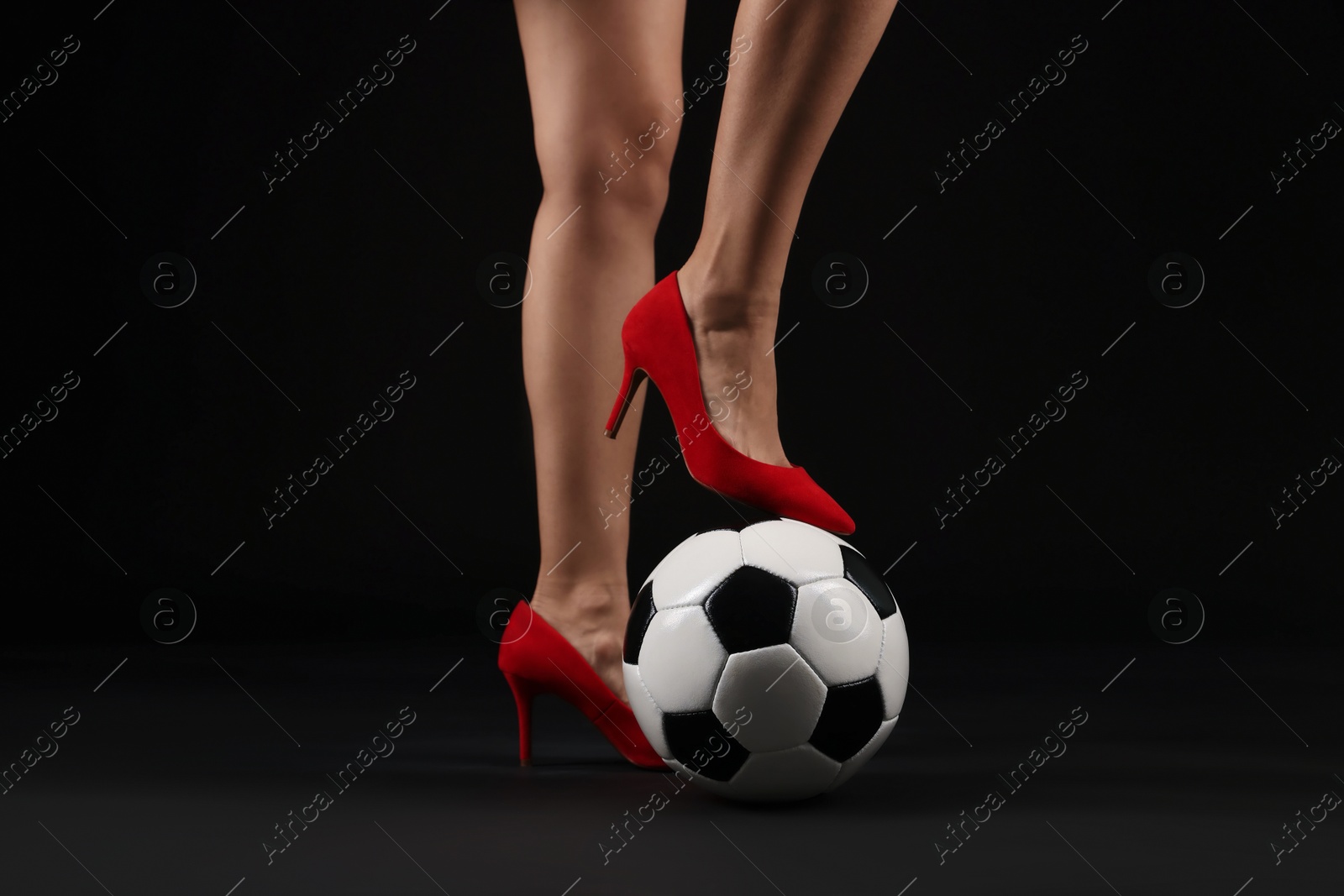 Woman in high heeled shoes with soccer ball on dark background, closeup Photo of Woman in high heeled shoes with soccer ball on dark background, closeup