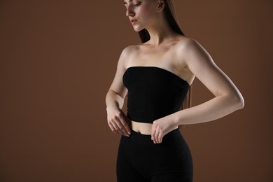 Photo of Woman with beautiful body on brown background, closeup. Space for text