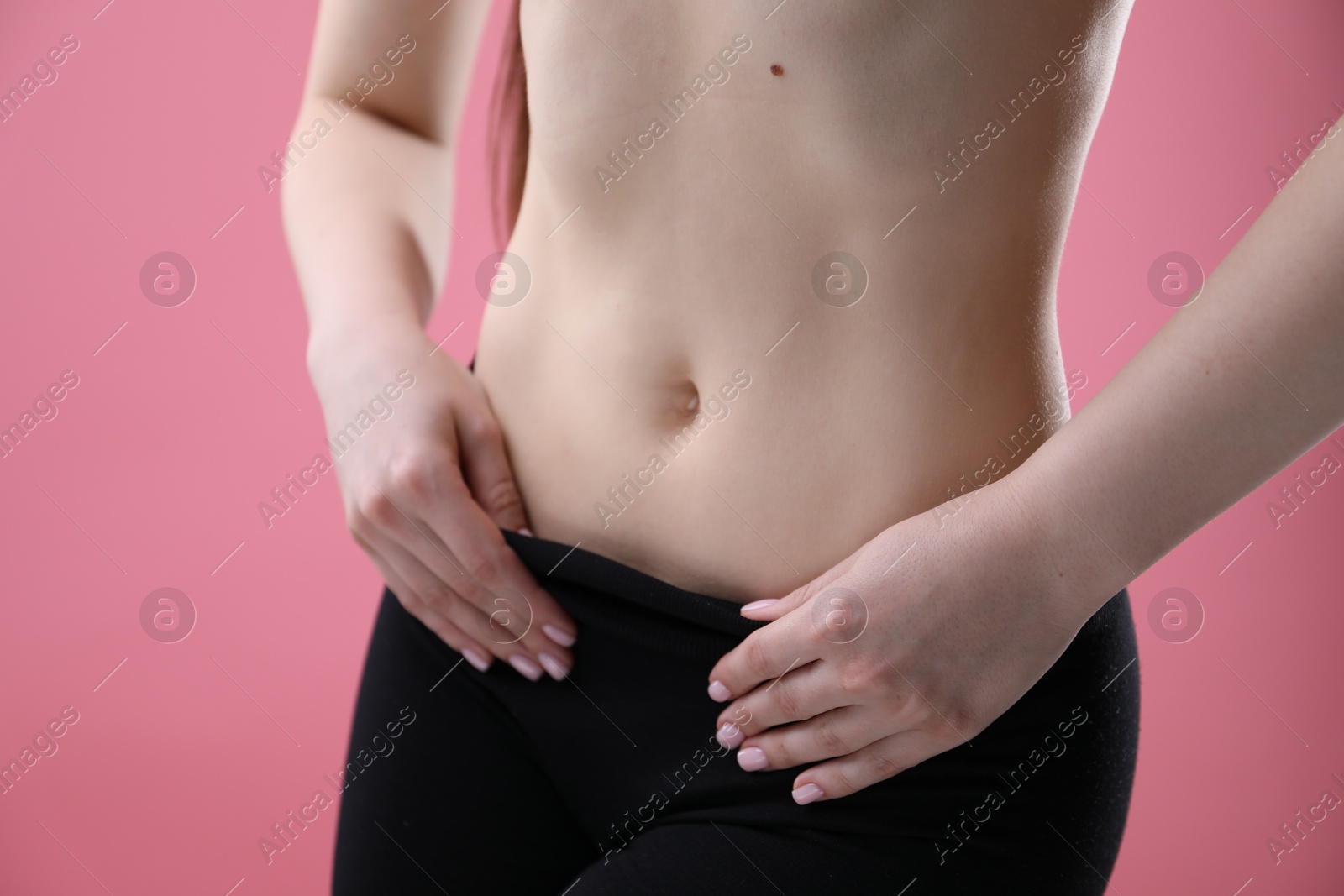 Attractive woman against pink background, closeup on belly Photo of Attractive woman against pink background, closeup on belly