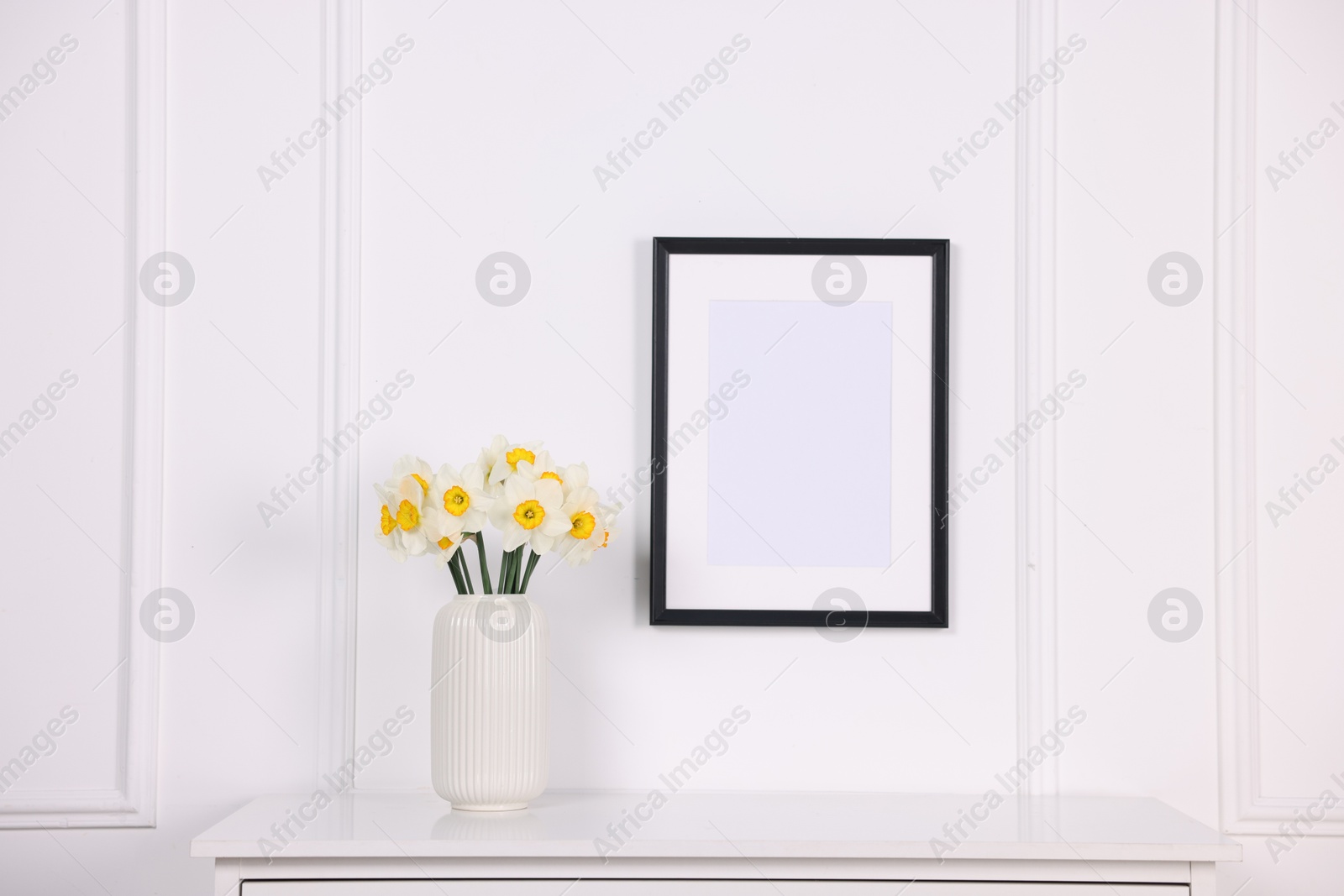 Beautiful daffodils in vase on dresser and picture frame at home Photo of Beautiful daffodils in vase on dresser and picture frame at home