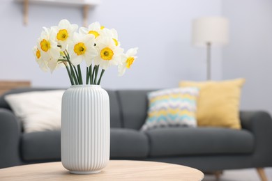 Photo of Beautiful daffodils in vase on wooden table indoors, space for text