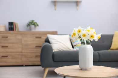 Photo of Beautiful daffodils in vase on wooden table indoors, space for text