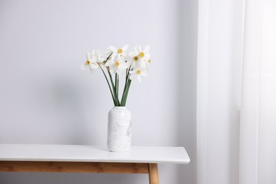 Photo of Beautiful daffodils in vase on white table indoors