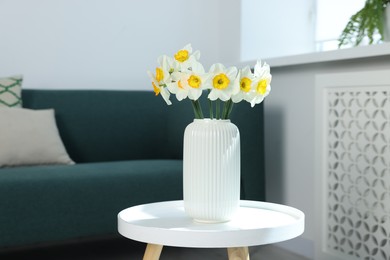 Photo of Beautiful daffodils in vase on table indoors