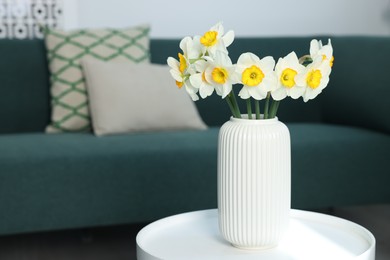 Photo of Beautiful daffodils in vase on table indoors, space for text
