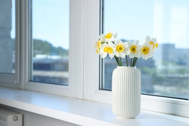 Photo of Beautiful daffodils in vase on window sill indoors