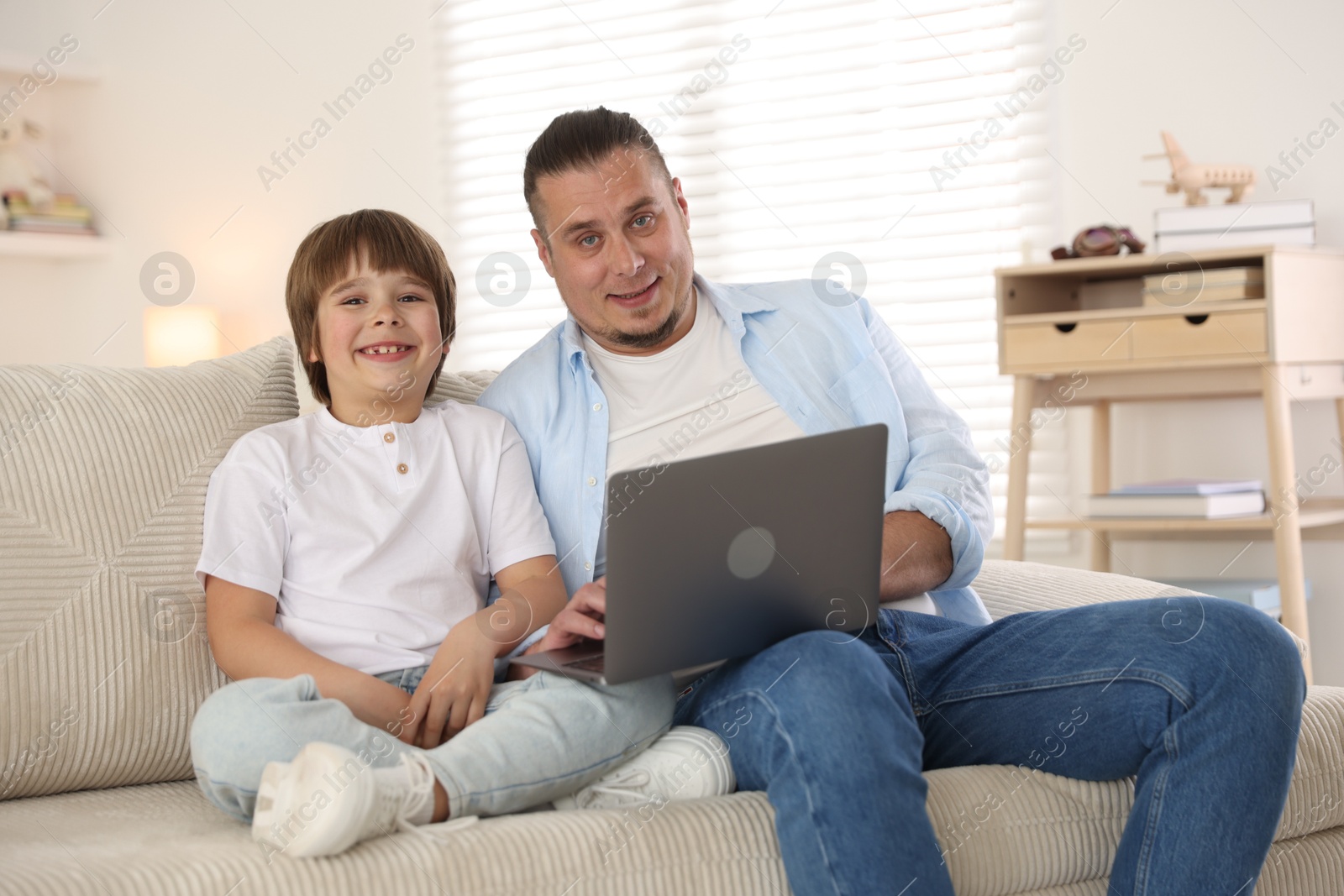 Father and his son watching something on laptop at home Photo of Father and his son watching something on laptop at home