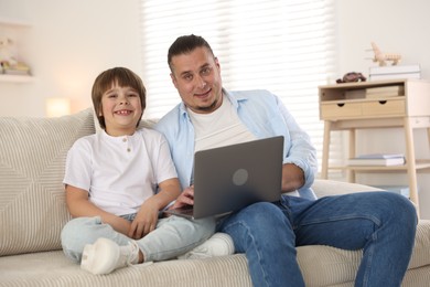 Photo of Father and his son watching something on laptop at home