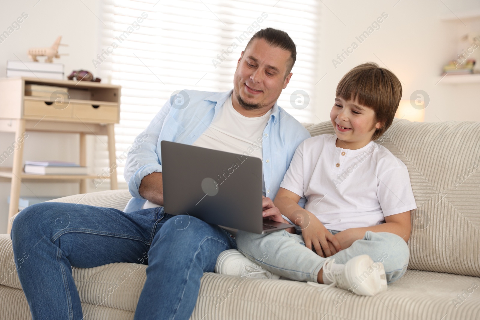 Father and his son watching something on laptop at home Photo of Father and his son watching something on laptop at home