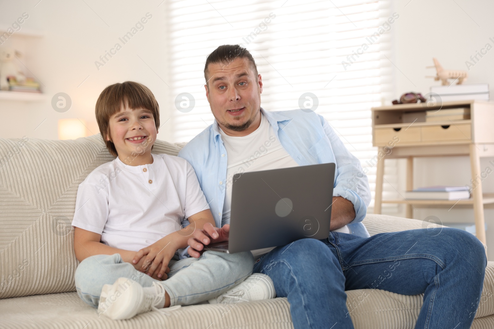 Father and his son watching something on laptop at home Photo of Father and his son watching something on laptop at home
