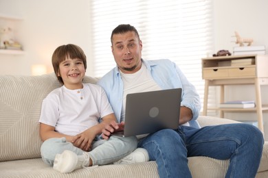 Photo of Father and his son watching something on laptop at home