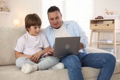 Photo of Father and his son watching something on laptop at home