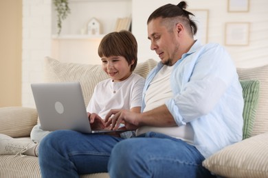 Photo of Father and his son watching something on laptop at home