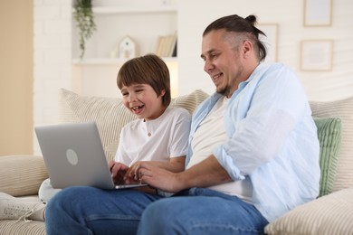 Photo of Father and his son watching something on laptop at home
