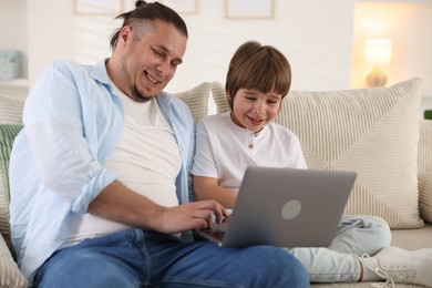 Photo of Father and his son watching something on laptop at home