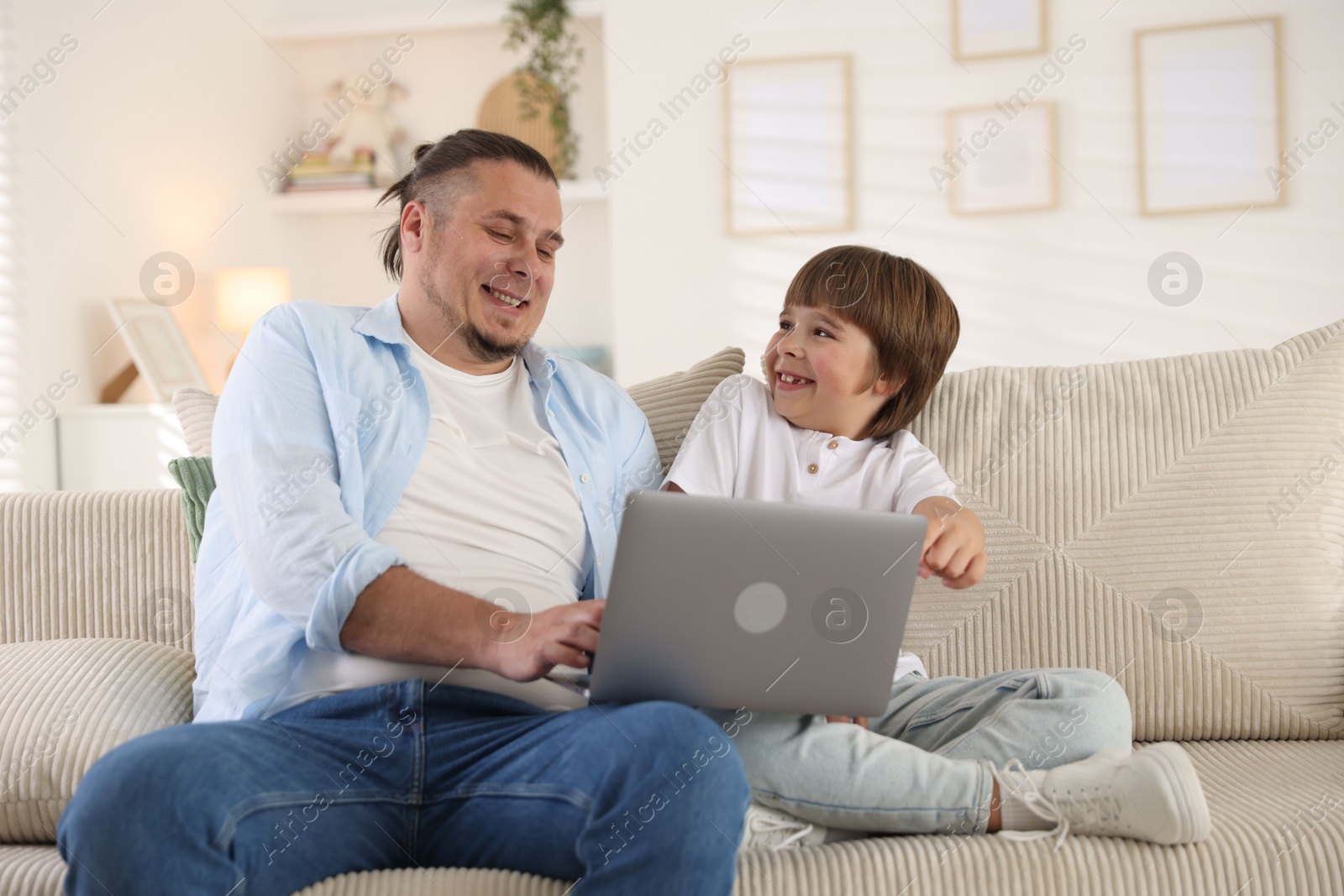 Father and his son watching something on laptop at home Photo of Father and his son watching something on laptop at home