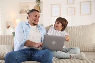 Photo of Father and his son watching something on laptop at home