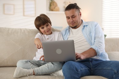 Photo of Father and his son watching something on laptop at home