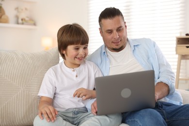 Photo of Father and his son watching something on laptop at home