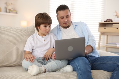 Photo of Father and his son watching something on laptop at home