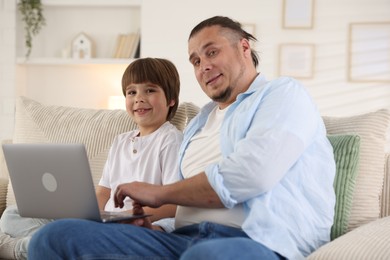 Photo of Father and his son watching something on laptop at home