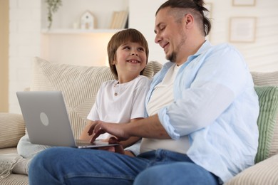 Photo of Father and his son watching something on laptop at home
